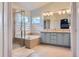 Bright bathroom with tiled floor, glass shower, jacuzzi style tub, double sinks and globe lighting at 9921 W Edenburg Pl, Littleton, CO 80127