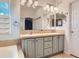 Bathroom featuring double sinks, with a large mirror, globe lighting and tan tile backsplash at 9921 W Edenburg Pl, Littleton, CO 80127