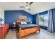 Comfortable bedroom features blue accent wall, wooden bed frame, and lots of natural light from the window at 9921 W Edenburg Pl, Littleton, CO 80127