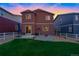 Backyard at dusk featuring green lawn, concrete patio, and a fenced perimeter for privacy at 5311 Blue Lunar Ln, Castle Rock, CO 80104