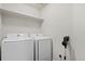 Functional laundry room with modern white washer and dryer and built-in shelf at 5311 Blue Lunar Ln, Castle Rock, CO 80104