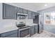 A modern kitchen featuring stainless steel appliances, gray cabinets, white countertops, and white subway tile backsplash at 7008 Ralston Rd, Arvada, CO 80002