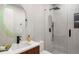 Modern bathroom with a glass enclosed shower and a circular mirror over a floating wood and white sink at 1518 S Columbine St, Denver, CO 80210