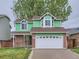 Two-story home with green siding, brick accents, and a two-car garage at 12025 Monaco Dr, Brighton, CO 80602