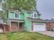 Green home with a two-car garage and partial brick facade at 12025 Monaco Dr, Brighton, CO 80602