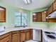 A cozy kitchen features wood cabinets, a stainless steel dishwasher, and a bright window at 12025 Monaco Dr, Brighton, CO 80602