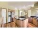 Open kitchen with stainless steel refrigerator, cooktop island, hardwood floors and easy access to additional living spaces at 9742 E Hawaii Pl, Aurora, CO 80247