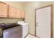 A laundry room with a light wood cabinets, a washer and dryer, and white door at 9742 E Hawaii Pl, Aurora, CO 80247