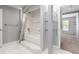Bathroom with a white tiled tub and shower, glass shelving, and view into bedroom at 1521 Vine St # 108, Denver, CO 80206