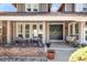 Inviting covered front porch with stone detailing, comfortable seating, and stylish double door entrance at 5557 E Links Cir, Centennial, CO 80122
