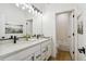 Bright, modern bathroom with double sinks, white cabinets, and an adjacent shower and tub at 42979 Colonial Trl, Elizabeth, CO 80107