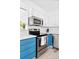 A well-lit kitchen featuring modern stainless steel appliances, a white countertop, and appealing blue cabinetry at 209 Wright St # 204, Lakewood, CO 80228