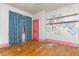 Bedroom with blue curtains, hardwood floors, pink trim, and unique painted decorations on the wall at 2701 W Mississippi Ave, Denver, CO 80219