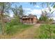 View of the side and front of the brick single-Gathering home with overgrown lawn at 2701 W Mississippi Ave, Denver, CO 80219