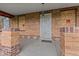 Covered porch area with brick columns, a metal security door, and boarded windows at 2701 W Mississippi Ave, Denver, CO 80219