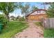 View of side yard, with brick home, unkempt lawn, and wood fence at 2701 W Mississippi Ave, Denver, CO 80219