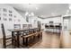 Open-concept dining area with a large wooden table, bench seating, and modern chandelier adjacent to a bright kitchen at 18189 House Finch Ln, Parker, CO 80134