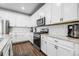Modern kitchen with stainless steel appliances, granite countertops, white cabinets, a stylish backsplash and hardwood flooring at 18189 House Finch Ln, Parker, CO 80134