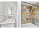 This updated bathroom has a large mirror, white sink, and a multicolored tiled shower-tub at 3854 Perry St, Denver, CO 80212