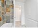 White bathroom includes a shower-tub with multicolored tiles, linen cabinet and a doorway to another space at 3854 Perry St, Denver, CO 80212