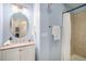 Well-lit bathroom featuring light blue walls, modern vanity, round mirror, and a shower with tiled walls at 1822 Painter Dr, Monument, CO 80132