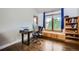 Bright office space with hardwood floors, a large window with bench seating, and a modern desk setup at 440 Scrub Oak Cir, Monument, CO 80132