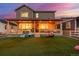 Inviting backyard with covered patio, lush lawn, and play area at twilight at 4925 Coltin Trl, Castle Rock, CO 80104