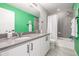 Bathroom featuring a double vanity, modern fixtures, and a shower/tub combo with green accent wall at 4925 Coltin Trl, Castle Rock, CO 80104