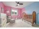 Bright Bedroom with a pink accent wall, wooden crib, comfortable seating, and soft carpeting at 4925 Coltin Trl, Castle Rock, CO 80104