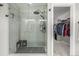 Contemporary glass shower featuring a bench, rainfall showerhead, and tile surround, with a walk-in closet view at 4925 Coltin Trl, Castle Rock, CO 80104
