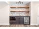 Basement bar area with stone backsplash, floating shelves, and beverage refrigerator at 7120 Red Mesa Dr, Littleton, CO 80125