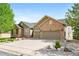 Beautiful home showcasing a manicured front yard, mature trees, brick accents, and attached two car garage at 7120 Red Mesa Dr, Littleton, CO 80125
