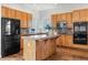Well-lit kitchen with a central island, wood cabinetry, and modern appliances at 7120 Red Mesa Dr, Littleton, CO 80125