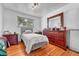 Bedroom featuring hardwood floors, a bed, a large dresser and a large mirror at 7940 Appleblossom Ln, Westminster, CO 80030