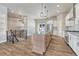 Open-concept kitchen featuring a center island, granite countertops, white cabinets, and wood-look tile flooring at 91 Greeley Blvd, Palmer Lake, CO 80133