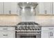 Modern kitchen features stainless steel stove, hood, and white cabinets at 91 Greeley Blvd, Palmer Lake, CO 80133