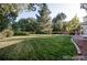 Expansive backyard with manicured lawn, mature trees, and a charming patio area at 7154 S Hudson Cir, Centennial, CO 80122