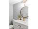 Chic powder room with round mirror, patterned wallpaper, and gold faucet, adding a touch of elegance at 7154 S Hudson Cir, Centennial, CO 80122