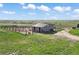 This aerial view showcases a barn with surrounding paddocks and a wide-open grassy landscape at 1705 Outter Marker Rd, Castle Rock, CO 80108
