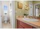 Bathroom with warm tones featuring wooden cabinets, sink, toilet and window at 7003 S Irvington Ct, Aurora, CO 80016