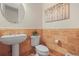 Charming powder room featuring brick-style walls, round mirror, and pedestal sink at 7003 S Irvington Ct, Aurora, CO 80016