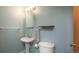 Bright bathroom with pedestal sink, toilet, open shelf, and wood-trimmed door at 6306 Xavier St, Arvada, CO 80003