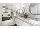 Bright bathroom featuring dual sinks, sleek countertops, and stylish round mirrors over white cabinets at 6306 Xavier St, Arvada, CO 80003