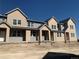 New townhouse construction featuring gray and tan siding with unfinished yard and landscaping at 17143 W 91St Ln, Arvada, CO 80007