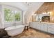 Luxurious bathroom with soaking tub, dual sinks, marble countertops, decorative chandelier, and large window with shutters at 115 S Glencoe, Denver, CO 80246