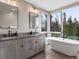 Bright bathroom featuring dual vanities, soaking tub, and large window with forest views at 436 N Fuller Placer Rd, Breckenridge, CO 80424