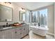 Bright bathroom featuring double vanity and soaking tub with beautiful view of surrounding mountains and trees at 436 N Fuller Placer Rd, Breckenridge, CO 80424