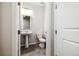 Clean half bathroom with a pedestal sink, white toilet, and a modern light fixture at 8609 Cheraw St, Littleton, CO 80125