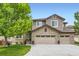 Charming home featuring a brick and siding exterior, three-car garage, manicured lawn, and mature tree at 989 Graland Pl, Highlands Ranch, CO 80126