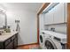Bathroom with a dark vanity, modern fixtures, and convenient in-unit laundry at 1217 Lincoln St, Longmont, CO 80501